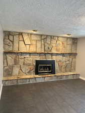 Details with baseboards, a textured ceiling, and a stone fireplace