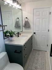 Bathroom with toilet, tile patterned floors, and vanity
