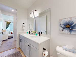 Ensuite bathroom with wood finished floors, connected bathroom, double vanity, toilet, and a sink