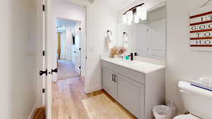 Half bathroom with toilet, wood finished floors, vanity, and baseboards