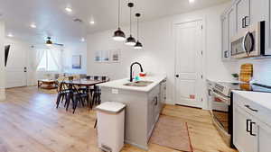 Kitchen featuring a sink, appliances with stainless steel finishes, visible vents, light wood-type flooring, and a peninsula