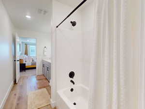 Ensuite bathroom with ensuite bathroom, baseboards, shower / tub combo with curtain, wood finished floors, and vanity