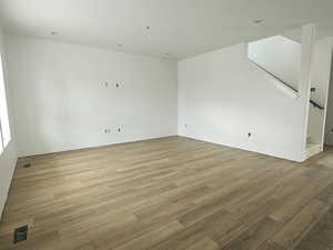 Unfurnished room with light wood-style flooring and stairs