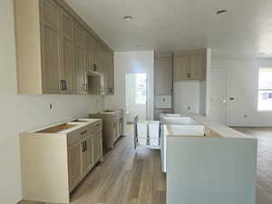 Kitchen featuring a textured ceiling, a kitchen island, and light wood finished floors
