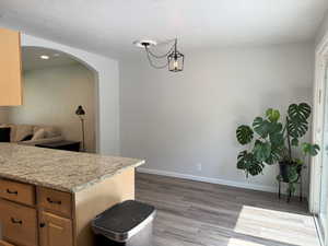 Kitchen featuring recessed lighting, light brown cabinets, baseboards, arched walkways, and wood finished floors