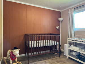 Bedroom with wood finished floors and ornamental molding