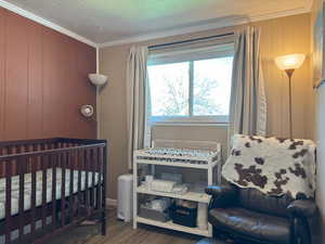 Bedroom with crown molding and wood finished floors