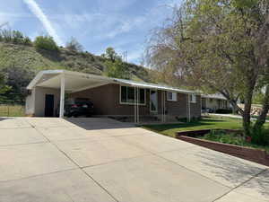Ranch-style home with driveway, a carport, a front yard, and brick siding