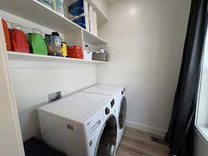 Washroom featuring laundry area, visible vents, wood finished floors, washer and dryer, and baseboards