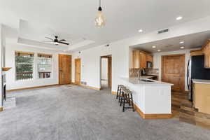 Kitchen featuring quartz countertops, a ceiling fan, and counter seating