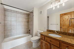 Full bath featuring vanity, tile patterned floors, toilet, and  shower combination