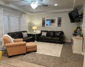 Living room featuring light wood-style flooring, a tray ceiling, baseboards, recessed lighting, and a ceiling fan