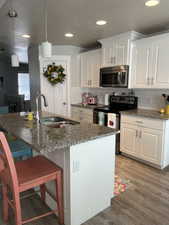 Kitchen with dark stone counters, white cabinets, appliances with stainless steel finishes, and a sink