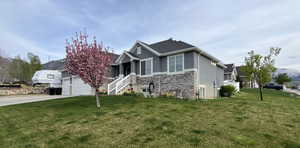 View of front of property featuring driveway, stone siding, a front yard, stucco siding, and a garage