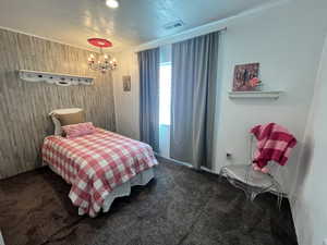 Carpeted bedroom with a chandelier, wood walls,