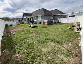 Back of house featuring a lawn, stucco siding, a fenced backyard, and roof with shingles