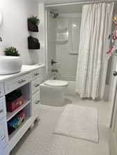 Bathroom featuring shower / tub combo, toilet, tile patterned flooring, and vanity