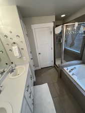Full bathroom with a shower stall, a sink, double vanity, a garden tub, and tile patterned flooring