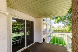 View of patio with large banister, built in gas line for BBQ, patio table, with view of waterfall pool and playground.