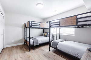 Front bedroom with closet, LVP flooring, fully furnished with bunkbeds, dresser and smart TV.