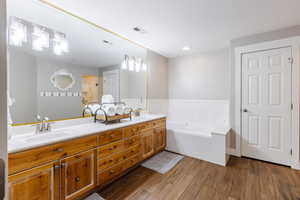 Solid wood double vanity, soaker tub, wood grain tile, and ensuite water closet.