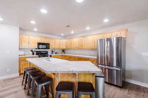 LVP flooring, fully stocked kitchen, stainless steel fridge, and barstools.