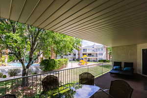 View of patio with large banister, built in gas line for BBQ, patio table, with view of waterfall pool and playground.