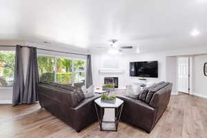 Family room with 75" TV, LVP flooring, recessed lighting, and 2 sliders.
