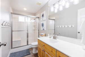 Full bathroom featuring vanity, toilet, LVP flooring, and  walk-in shower.