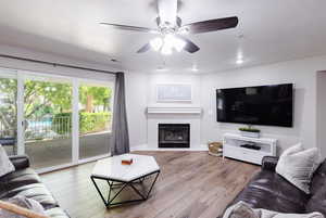 Family room with 75" TV, LVP flooring, recessed lighting, Hunter fan, and two sliders.