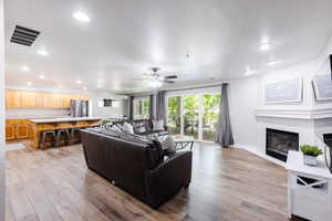 Family room with LVP flooring, two leather sofas, gas fireplace, mantle, floor to ceiling blackout draperies, and full kitchen.