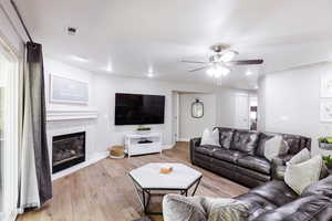 Family room with 75" TV, LVP flooring, recessed lighting, two leather sofas, and two sliders.
