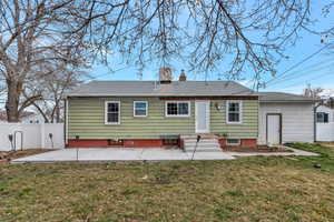 Rear view of property with a chimney, a patio area, fence, a yard, and a shingled roof