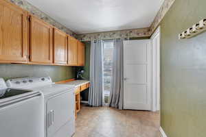 Washroom with baseboards, washing machine and dryer, and cabinet space