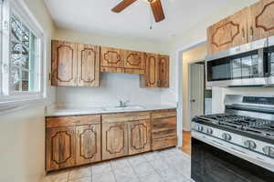 Kitchen featuring a sink, appliances with stainless steel finishes, ceiling fan, and light countertops