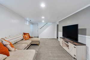 Living area with light colored carpet, ornamental molding, and recessed lighting