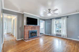 Unfurnished living room with wood-type flooring, visible vents, a fireplace, baseboards, and a ceiling fan