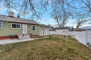 Back of house featuring a fenced backyard, a mountain view, a chimney, a playground, and a yard