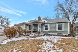 View of front of property with a garage, covered porch, a chimney, and a shingled roof