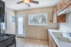 Kitchen featuring ceiling fan, electric panel, brown cabinetry, visible vents, and a sink