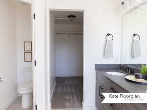 Full bathroom featuring vanity, baseboards, a spacious closet, and toilet