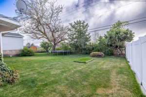 View of yard with a fenced backyard and a trampoline