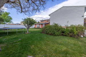 View of yard with a trampoline and fence