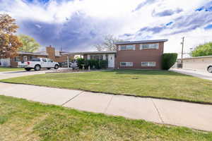 Tri-level home featuring brick siding and a front lawn