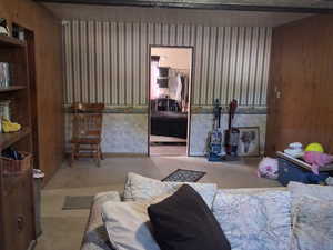 Living room with a textured ceiling, wooden walls, wallpapered walls, and carpet flooring