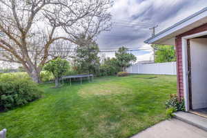 View of yard with fence and a trampoline