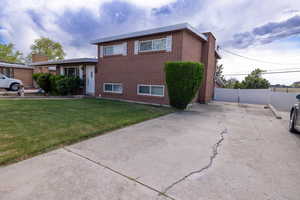 Tri-level home with brick siding, fence, and a front yard