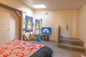 Carpeted bedroom featuring lofted ceiling with skylight and visible vents