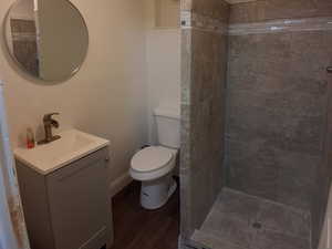 Full bath with vanity, a shower stall, a textured ceiling, and dark wood-type flooring