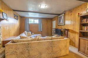 Living room featuring visible vents, a textured ceiling, wooden walls, and light carpet